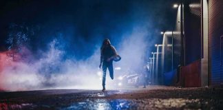 Person running at night near police car with flashing lights