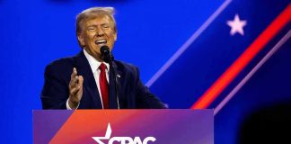 Donald Trump speaking at a podium on a brightly lit stage