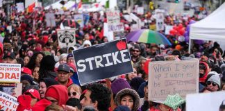Chuck Howley and Christian Jones in a large protest crowd holding strike signs