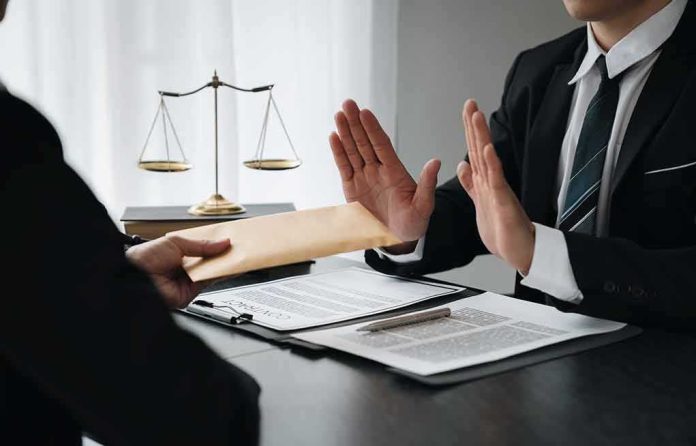 shutterstock_2290860255 Businessman refusing an envelope at a desk