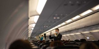 Flight attendant demonstrates safety procedures in airplane cabin
