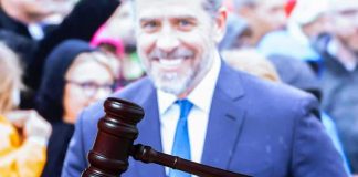 judge's gavel on desk with blurred suited man in background
