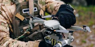 Soldier holding a quadcopter drone with attached device