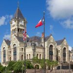 National Uproar Over Track Killing Historic stone courthouse with clock tower and flags