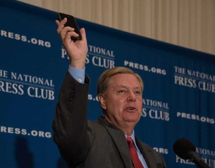 Man in suit speaking at podium holding up a smartphone