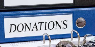 Blue binder labeled donations on a desk with papers and a calculator