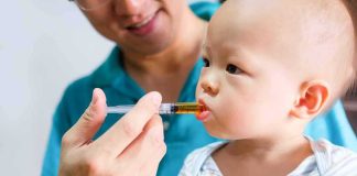 Judge Slams Surrogacy Pipeline Baby taking liquid medicine from an oral syringe held by an adult