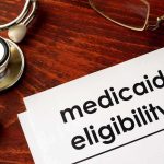 Gold, Properties Seized — Medicaid Scam Unraveled Medicaid eligibility form with stethoscope and pen on desk
