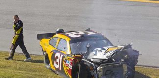 Race car with heavy front-end damage on grass
