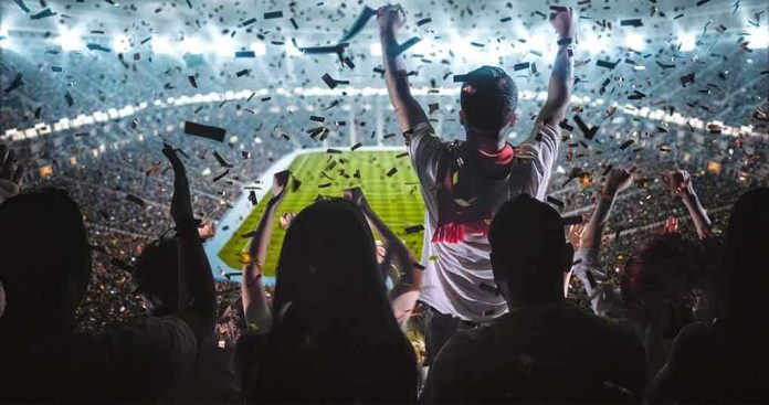 shutterstock_717281437 Fans celebrate in a packed stadium with confetti falling