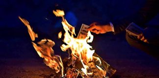 Paid To Quit? Bill Explodes Overnight Hands burning cash over a small fire at night