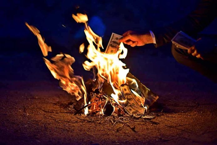 shutterstock_743708068 Hands burning cash over a small fire at night
