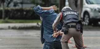 Ex-Spy Boss Nabbed – Treason Bombshell Police officer handcuffing person kneeling on pavement