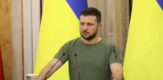 Full Stop or Trap? Ukraine’s Bold Gambit Man at a podium with Ukrainian flags