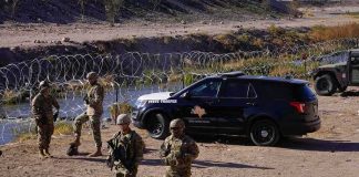 Border Calm? Massive Surge Raises Eyebrows Soldiers stand near barbed wire beside a police SUV