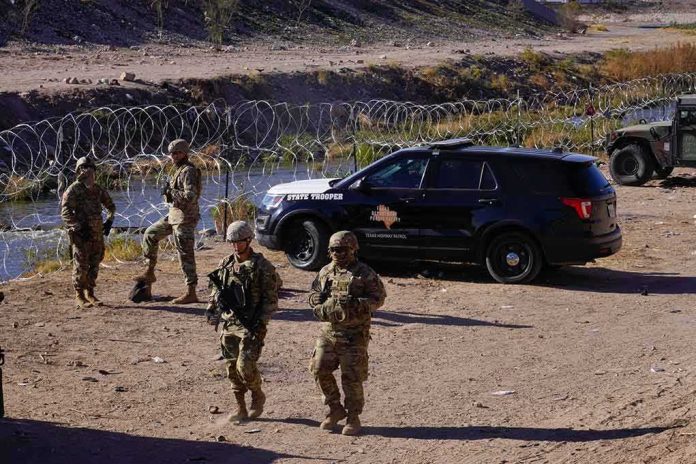 Soldiers stand near barbed wire beside a police SUV
