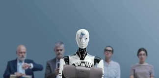 Jan-Peter Nikiferow seated with a humanoid robot holding a briefcase in front